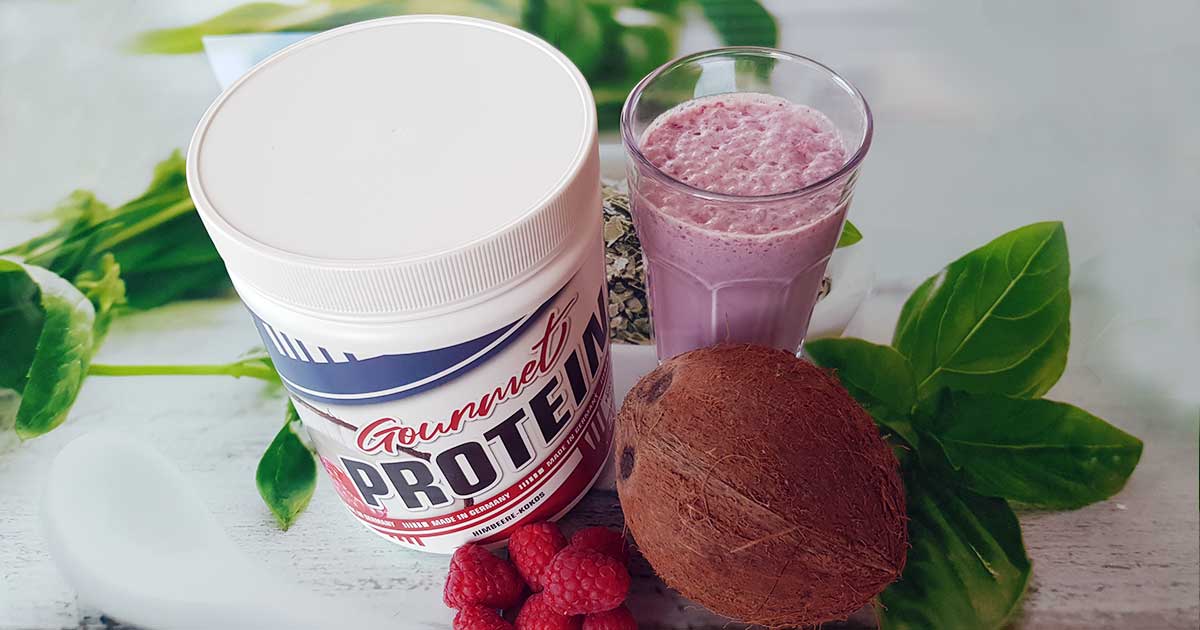 Bild zeigt Gourmet Protein, Kokosnuss, Himbeeren und ein Glas mit Shake