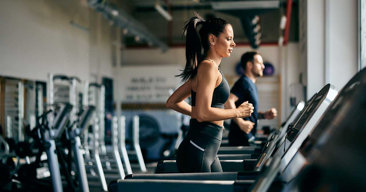 Frau läuft auf dem Laufband beim Cardio-Training im Fitnessstudio – Symbolbild für nüchternes Cardio.