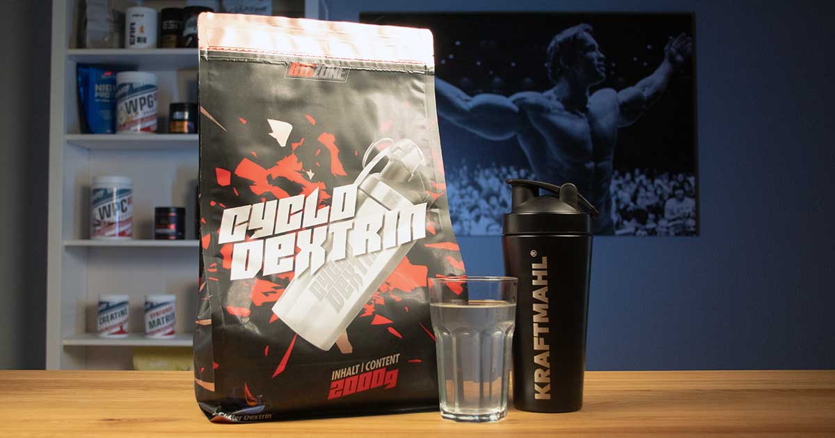 Big Zone Cyclo Dextrin im Kraftmahl Test – Produktfoto mit Shaker und Wasserglas auf Holztisch