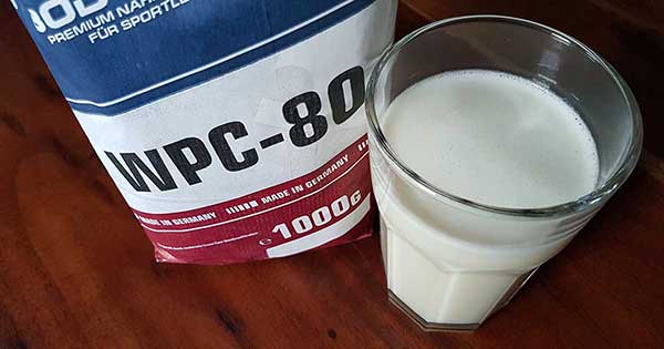 Bodybuilding Depot WPC-80 Whey-Konzentrat neben einem fertig gemixten Proteinshake im Glas