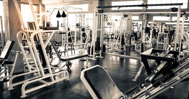 Bild zeigt Fitnessstudio mit Trainingsgeräten und Freihanteln