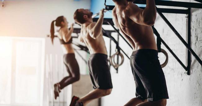 Bild zeigt wie zwei Männer und eine Frau Klimmzüge lernen