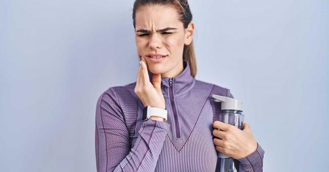 Bild zeigt Sportlerin mit Zahnschmerzen