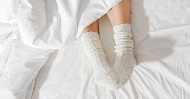 Bild zeigt Füße einer schlafenden Person im Bett