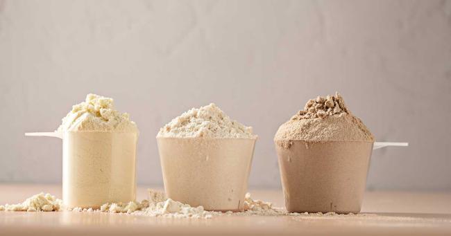 Mehrere Proteinpulver-Scoops als Symbol fĂŒr den Unterschied zwischen Whey Isolat und Konzentrat