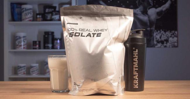 Prozis 100% Real Whey Isolate im Kraftmahl Test – angerührter Shake mit Shaker und Verpackung auf Holztisch.