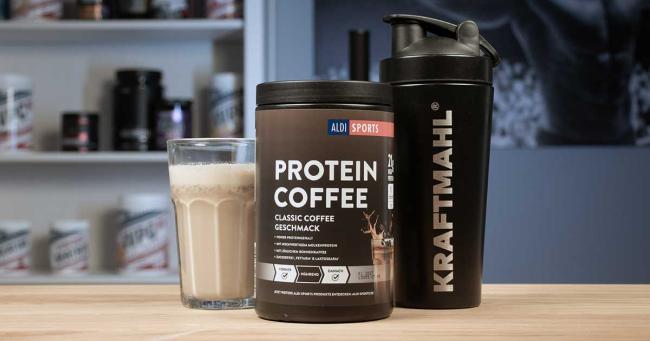 Aldi Sports Protein Coffee im Test: Produktdose neben gemixtem Shake im Glas und Kraftmahl-Shaker auf einem Holztisch.