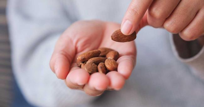 Hand mit Mandeln als Portion – gesunder Snack mit hoher Kaloriendichte