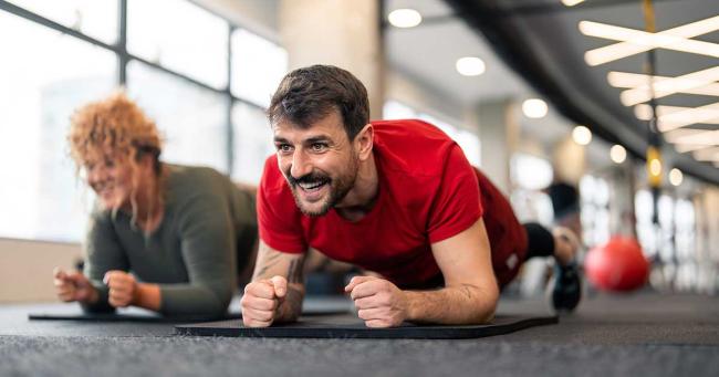 Mann führt im Fitnessstudio einen Plank (Unterarmstütz) zur Stärkung der Körpermitte aus