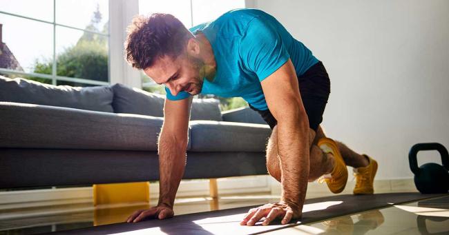 Mann macht intensives Homeworkout auf Matte im Wohnzimmer