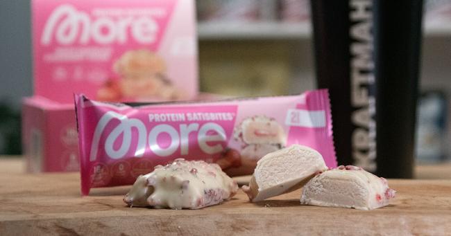 Angeschnittener More Protein Satisbites White Chocolate Strawberry Cream mit cremiger Füllung und weißem Schokoladenüberzug im Produkttest.