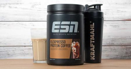 ESN Flexpresso Protein Coffee Dose mit gefülltem Glas und Kraftmahl-Shaker auf Holzuntergrund vor weißer Holzoptik