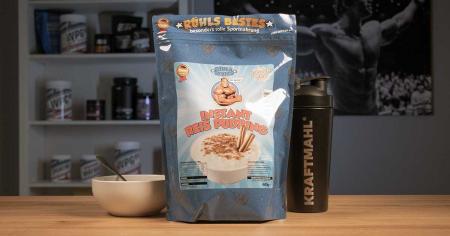 Rühls Bestes Instant Reispudding neben Kraftmahl Shaker und Schüssel auf Holztisch