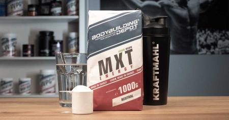 MXT Energy Maltodextrin von Bodybuilding Depot (1000 g, neutral) mit Messlöffel, Glas Wasser und schwarzem Kraftmahl-Shaker auf Holztisch.