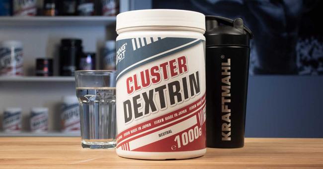 MXT Energy Maltodextrin von Bodybuilding Depot (1000 g, neutral) mit Messlöffel, Glas Wasser und schwarzem Kraftmahl-Shaker auf Holztisch.